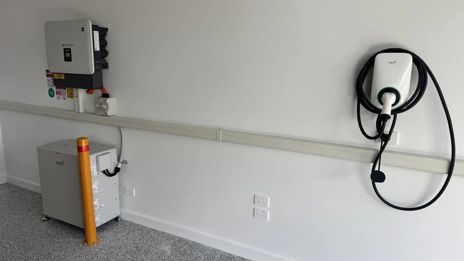A Fox ESS CQ7 battery stack beside its hybrid inverter, with a Fox ESS EV charger on the same garage wall, installed by Nuvolt