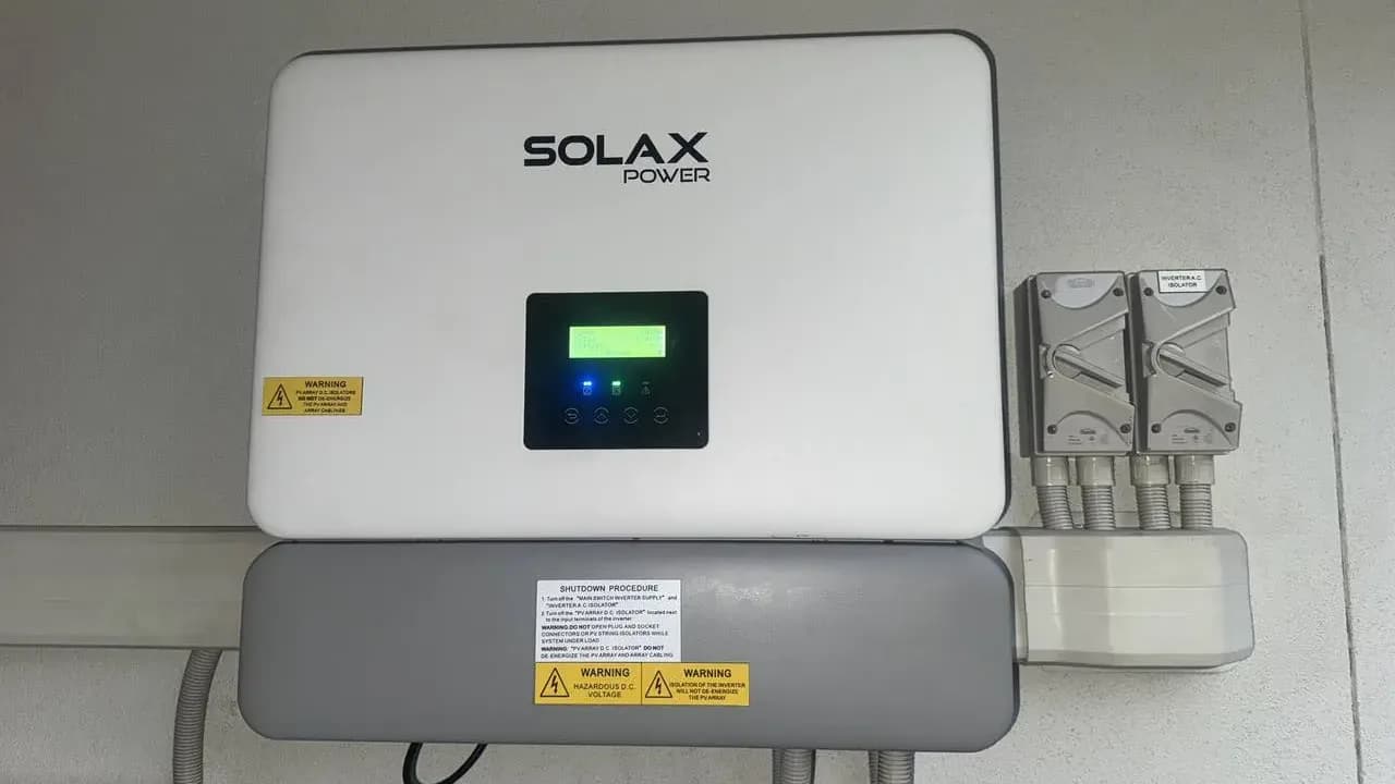 A SolaX hybrid inverter with its AC isolators, installed by Nuvolt on a garage wall in Buddina on the Sunshine Coast