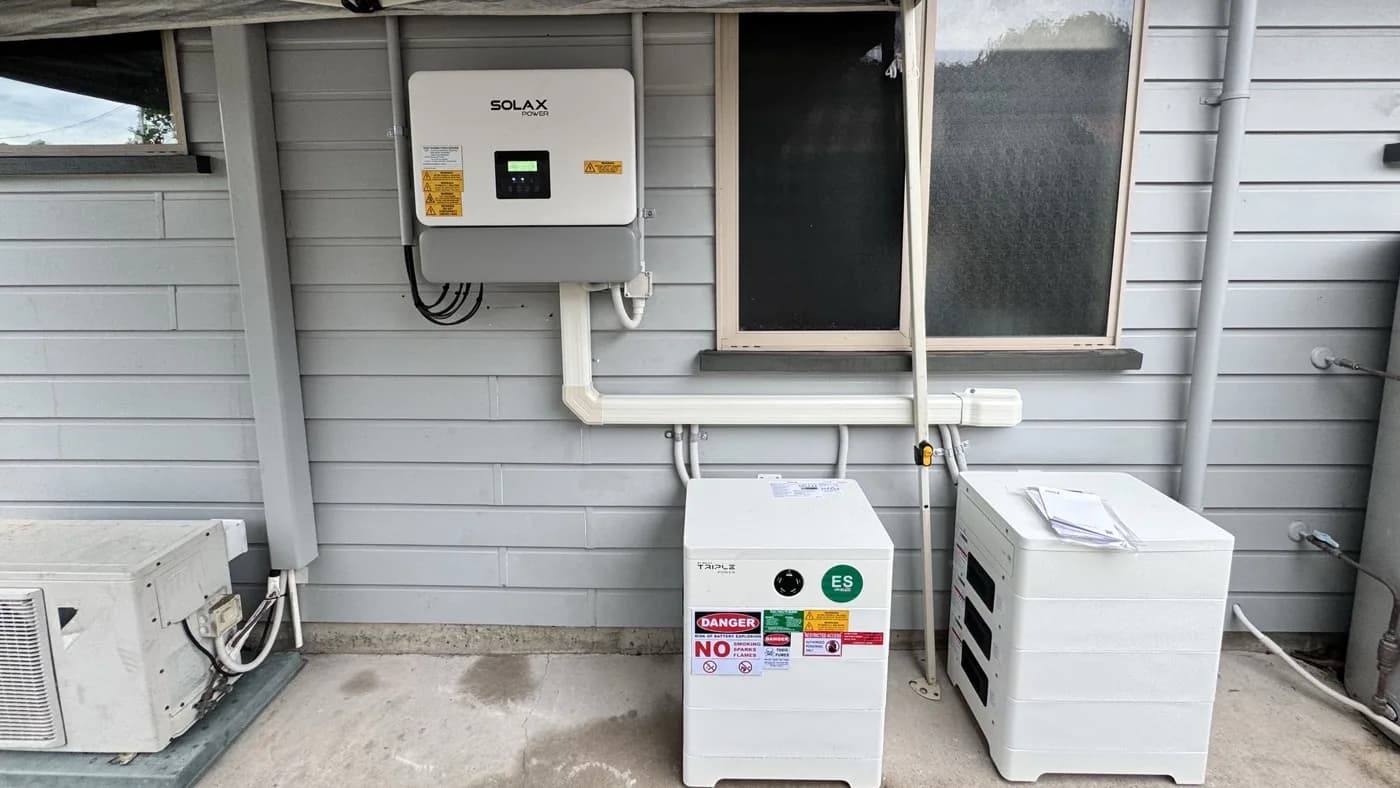 A SolaX hybrid inverter with two Triple Power battery stacks installed under cover on the outside wall of a Coolum Beach home, by Nuvolt