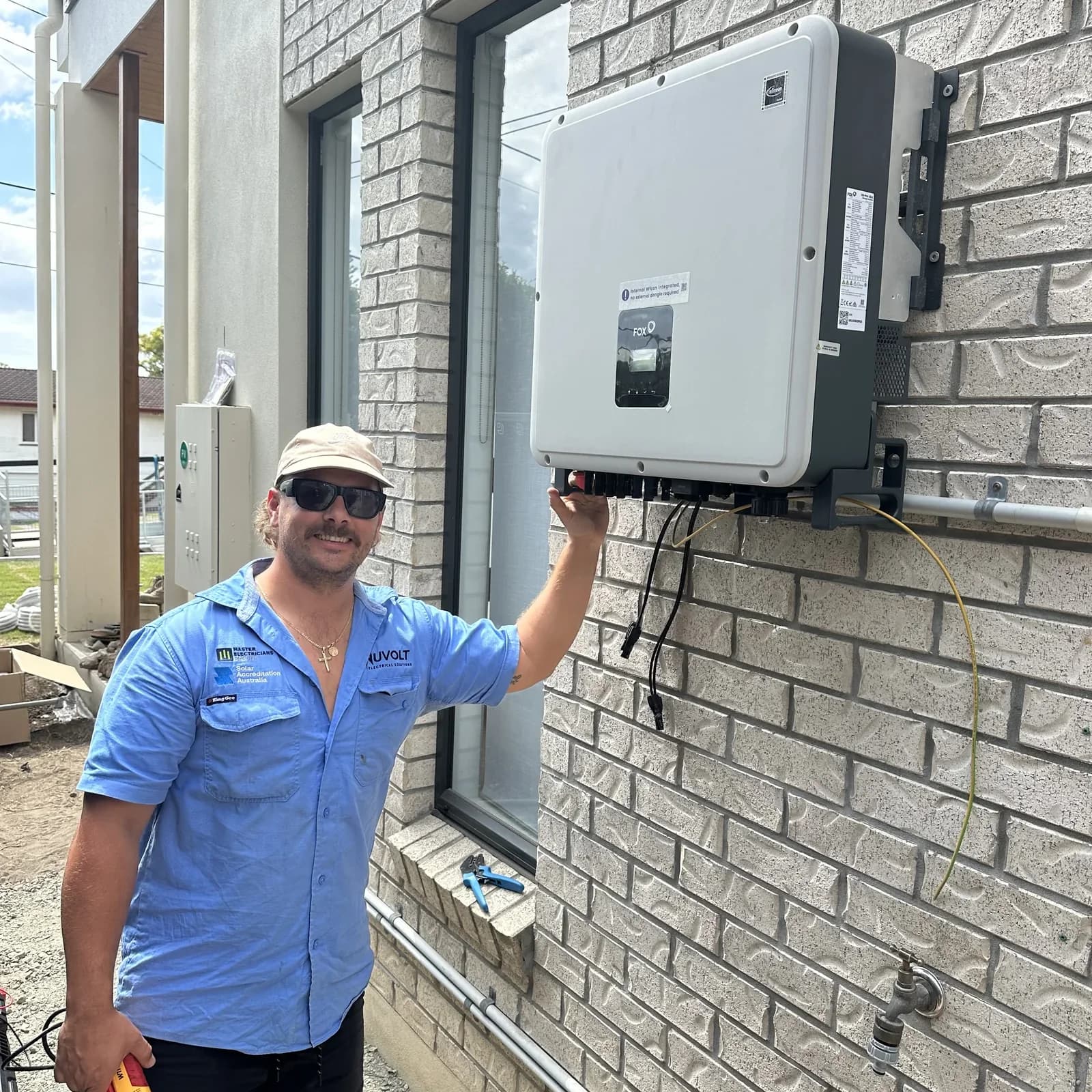 Nuvolt electrician fitting a Fox ESS hybrid inverter to the external wall of a home