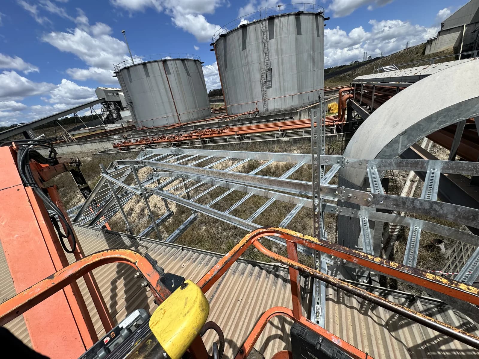 Galvanised cable ladder and tray run feeding bulk storage silos on a Queensland commercial site