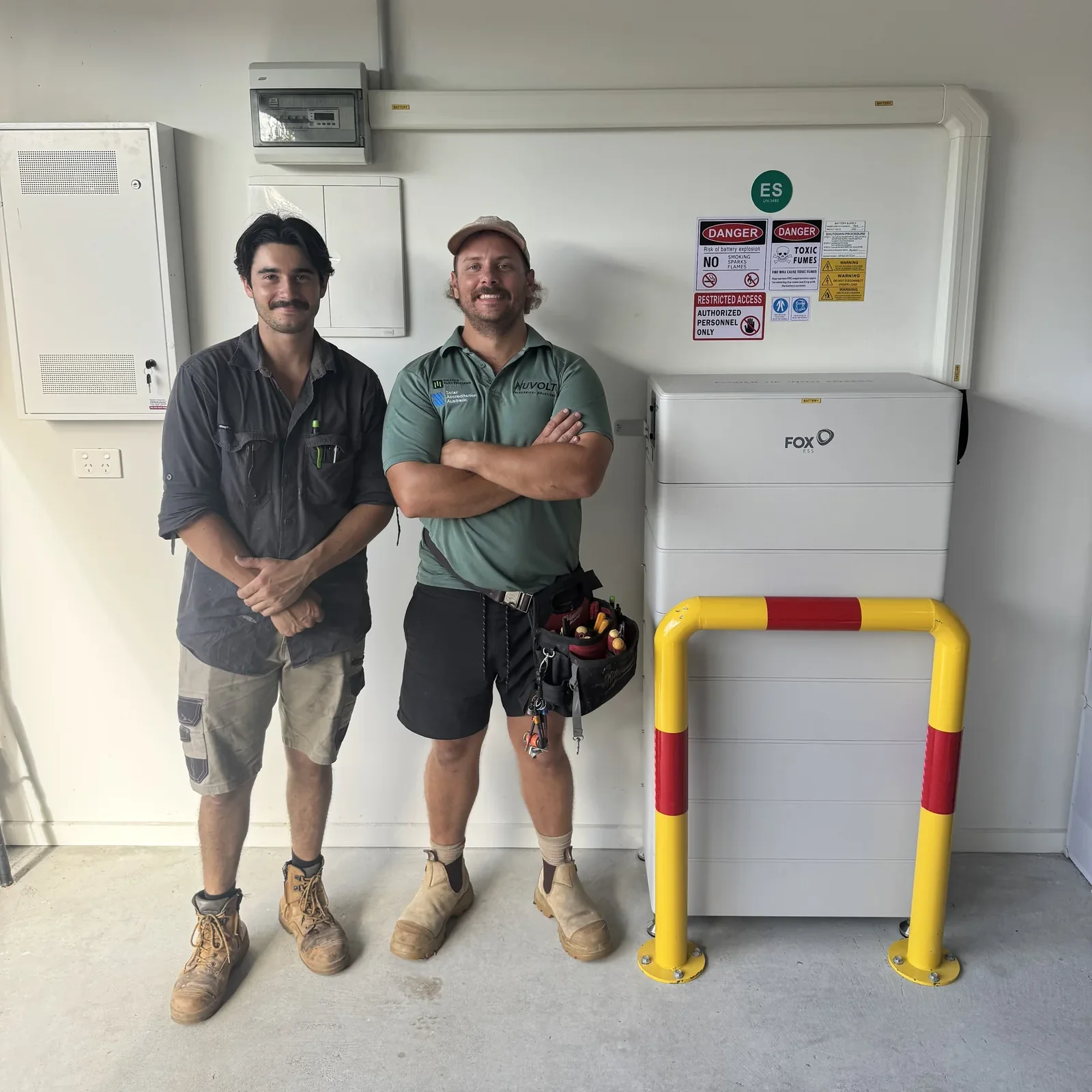 Two Nuvolt Electrical electricians beside a newly commissioned Fox ESS home battery in a garage