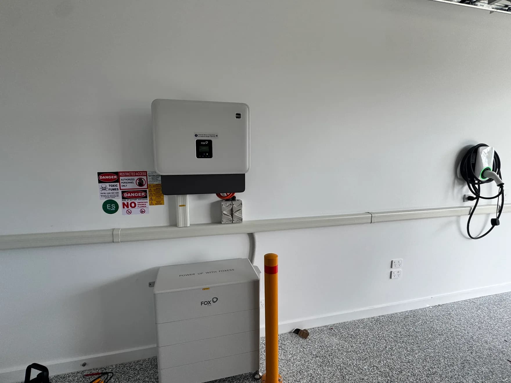 Fox ESS home battery and hybrid inverter installed in a Sunshine Coast garage by Nuvolt, with bollard protection and full safety signage