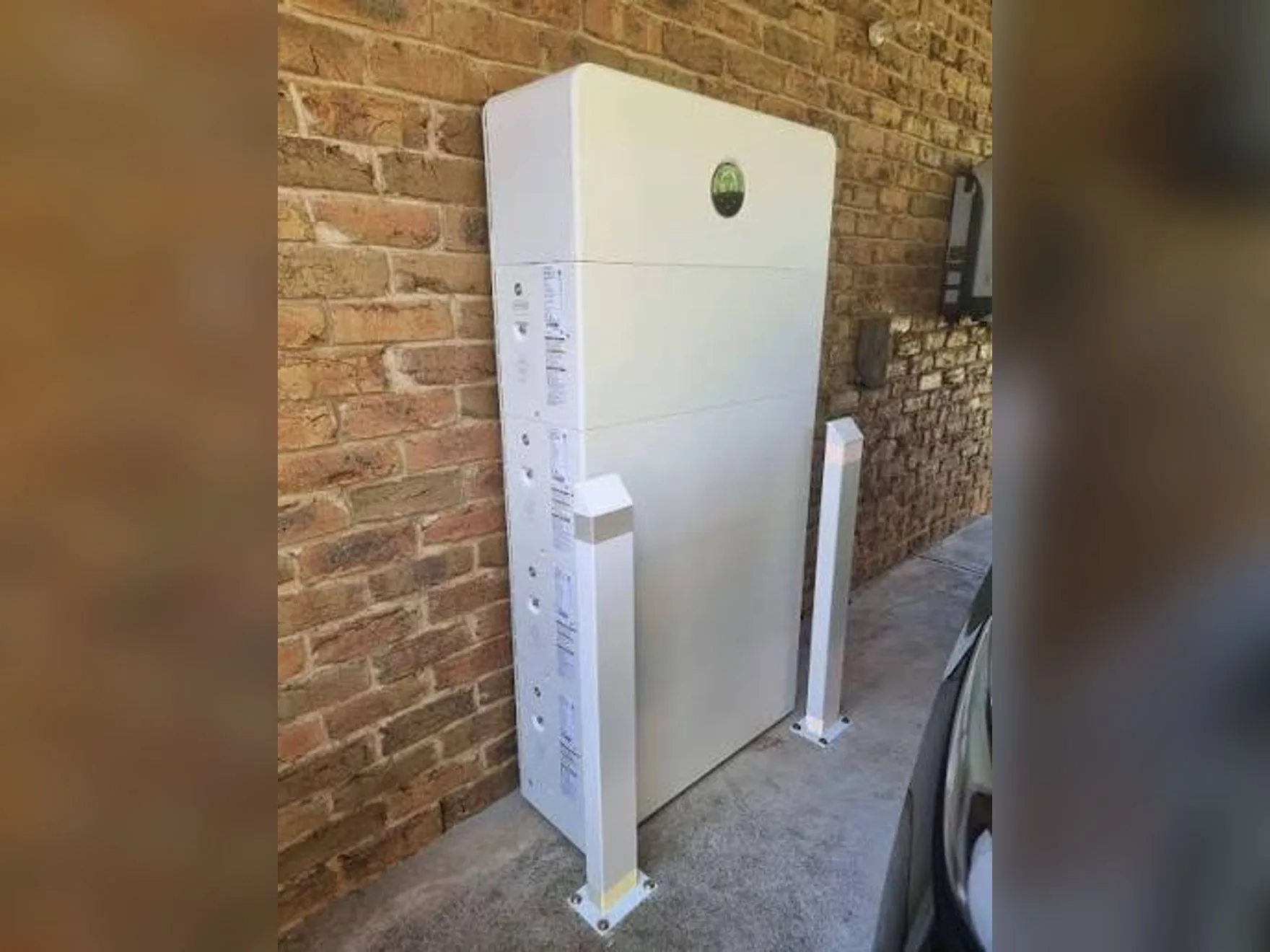 GoodWe ESA home battery installed against a brick wall by Nuvolt, with bollard protection either side