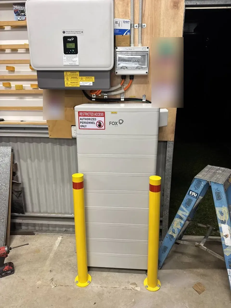 Fox ESS hybrid inverter and Fox ESS battery stack installed in a shed with protective bollards