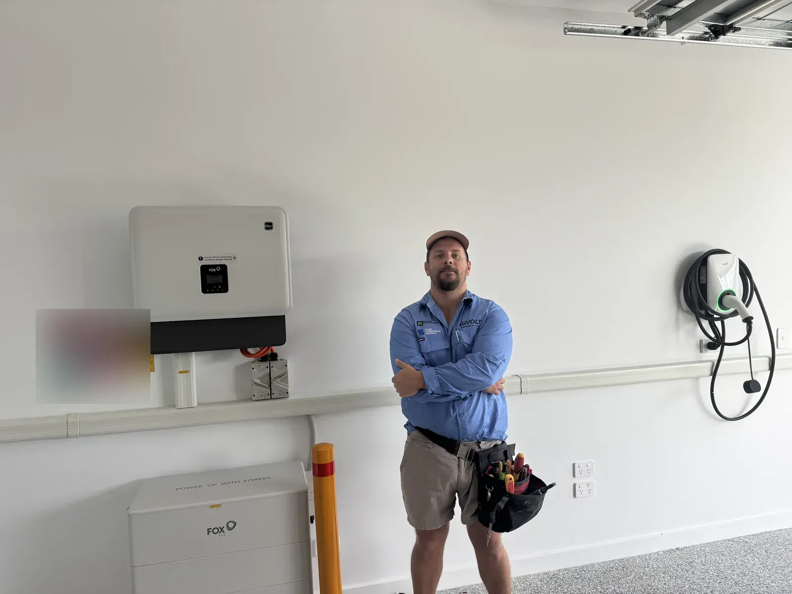 Nuvolt Electrical electrician beside a 28kWh Fox ESS CQ7 battery, 15kW H3 three phase hybrid inverter and 22kW EV charger in a garage