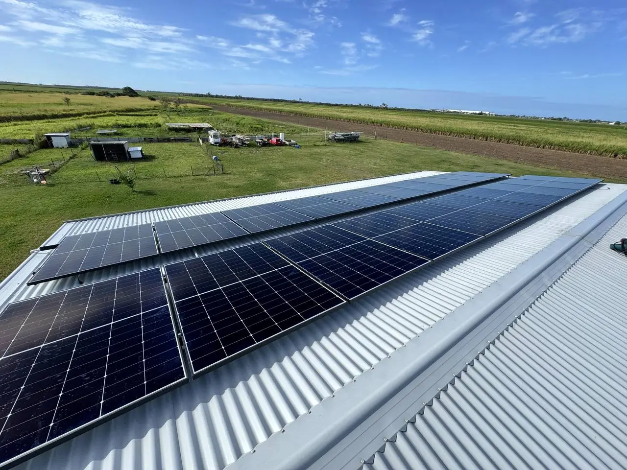 Nuvolt solar array installed across a rural shed roof, looking out over cane fields