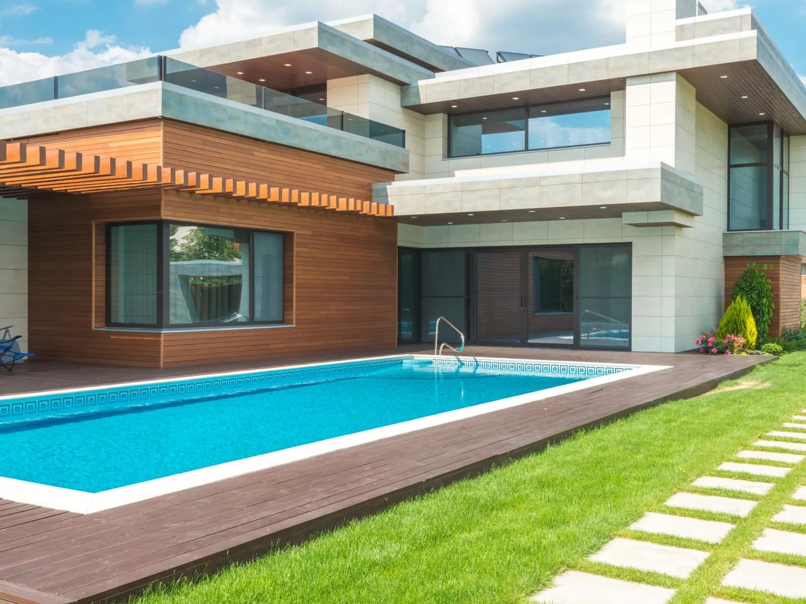 In ground swimming pool beside a modern home with timber decking and lawn