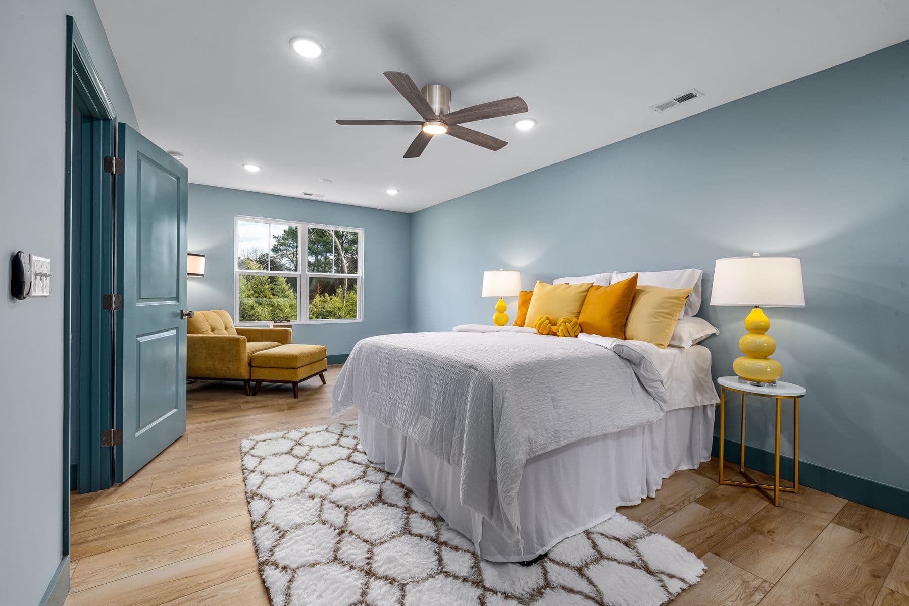 Modern ceiling fan with light and LED downlights in a bright bedroom