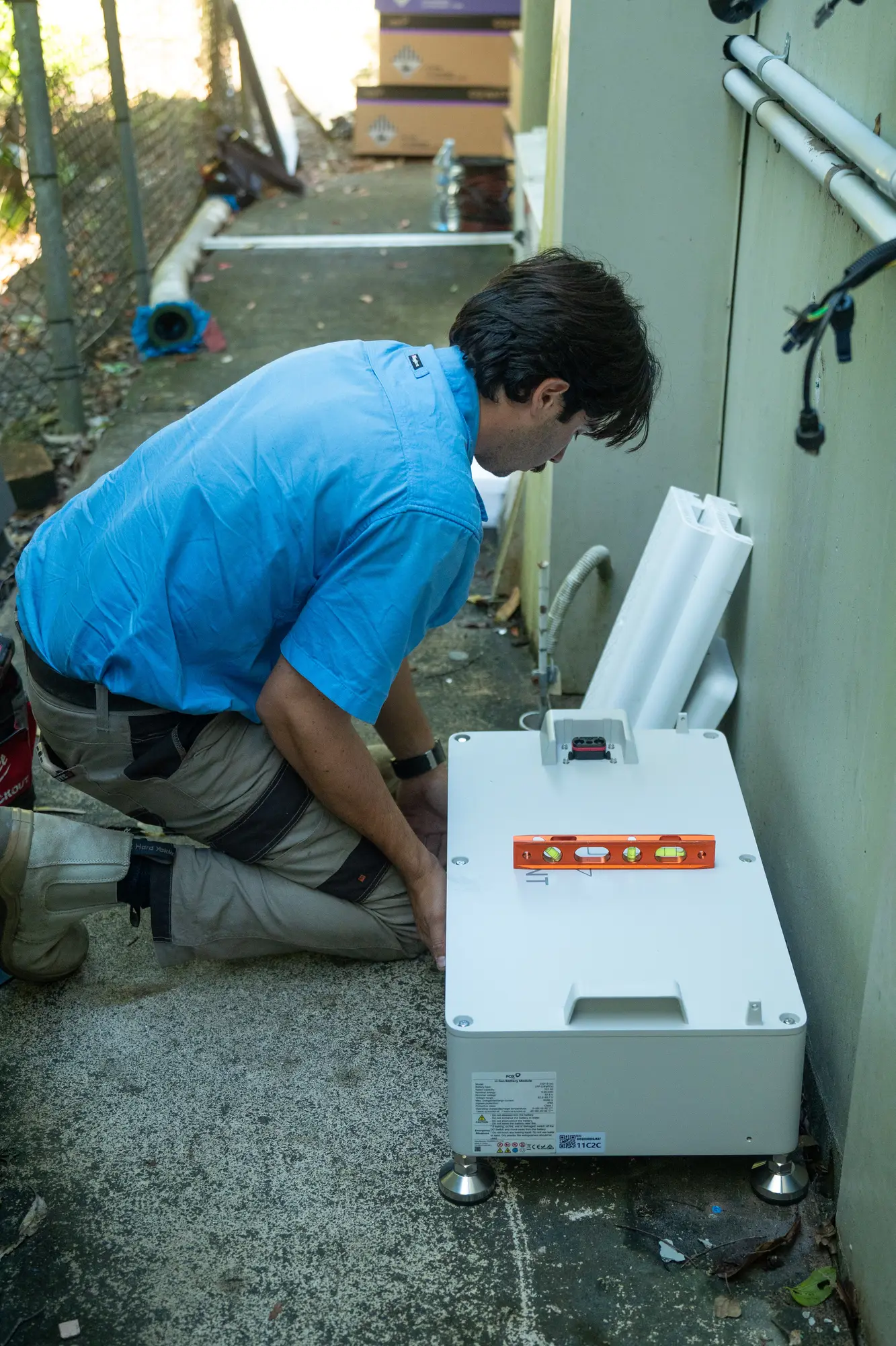 Dan and a Nuvolt team member beside a Fox ESS battery they are installing at a commercial site in Burnside