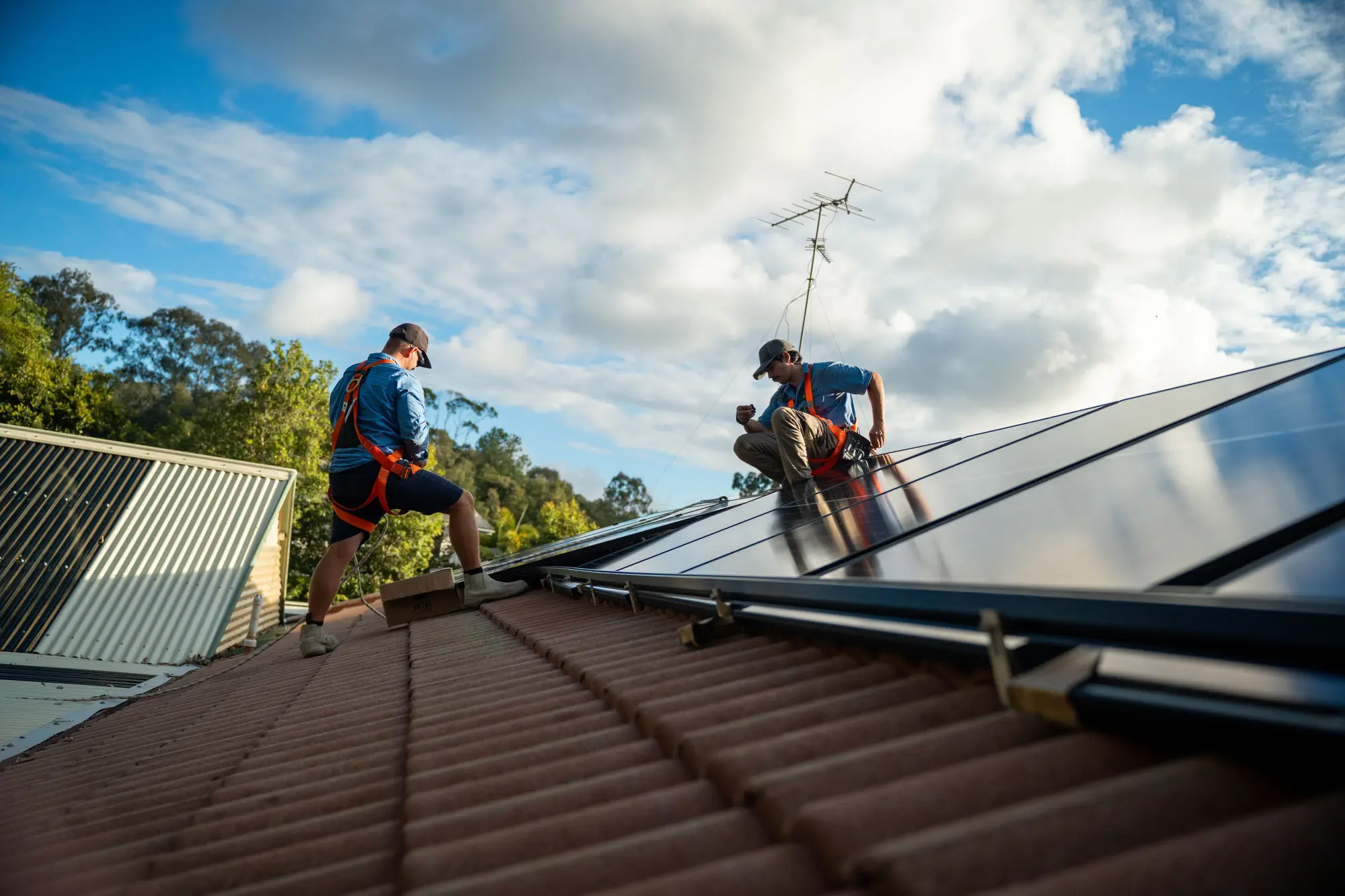 Dan from Nuvolt and a team member laying solar panels on a tiled roof on the Sunshine Coast