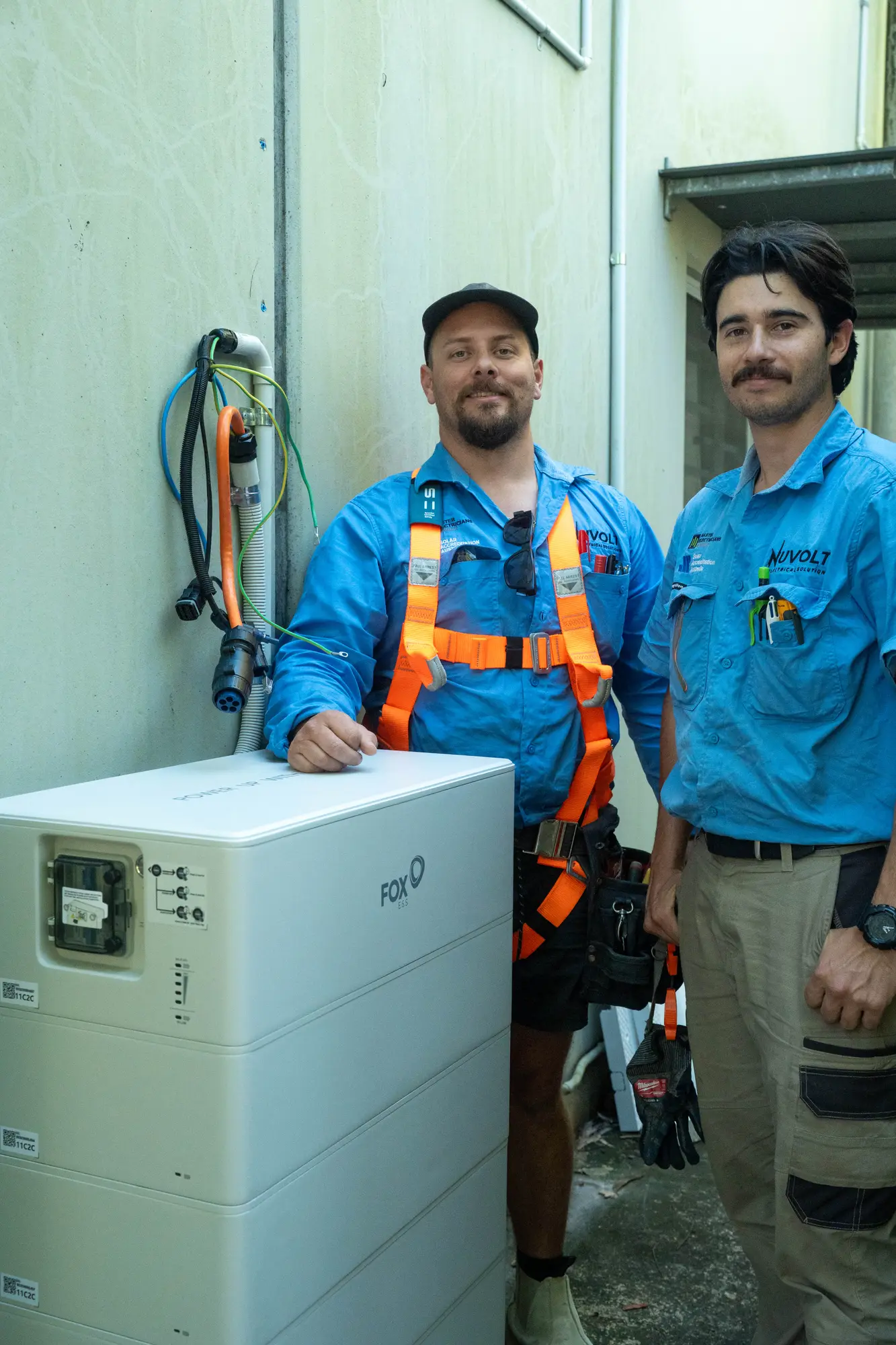 Dan and a Nuvolt team member beside a Fox ESS battery they are installing at a commercial site