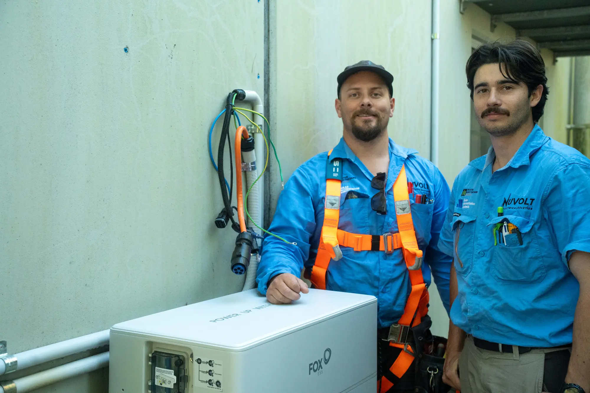 Dan and a Nuvolt team member beside a Fox ESS battery they are installing