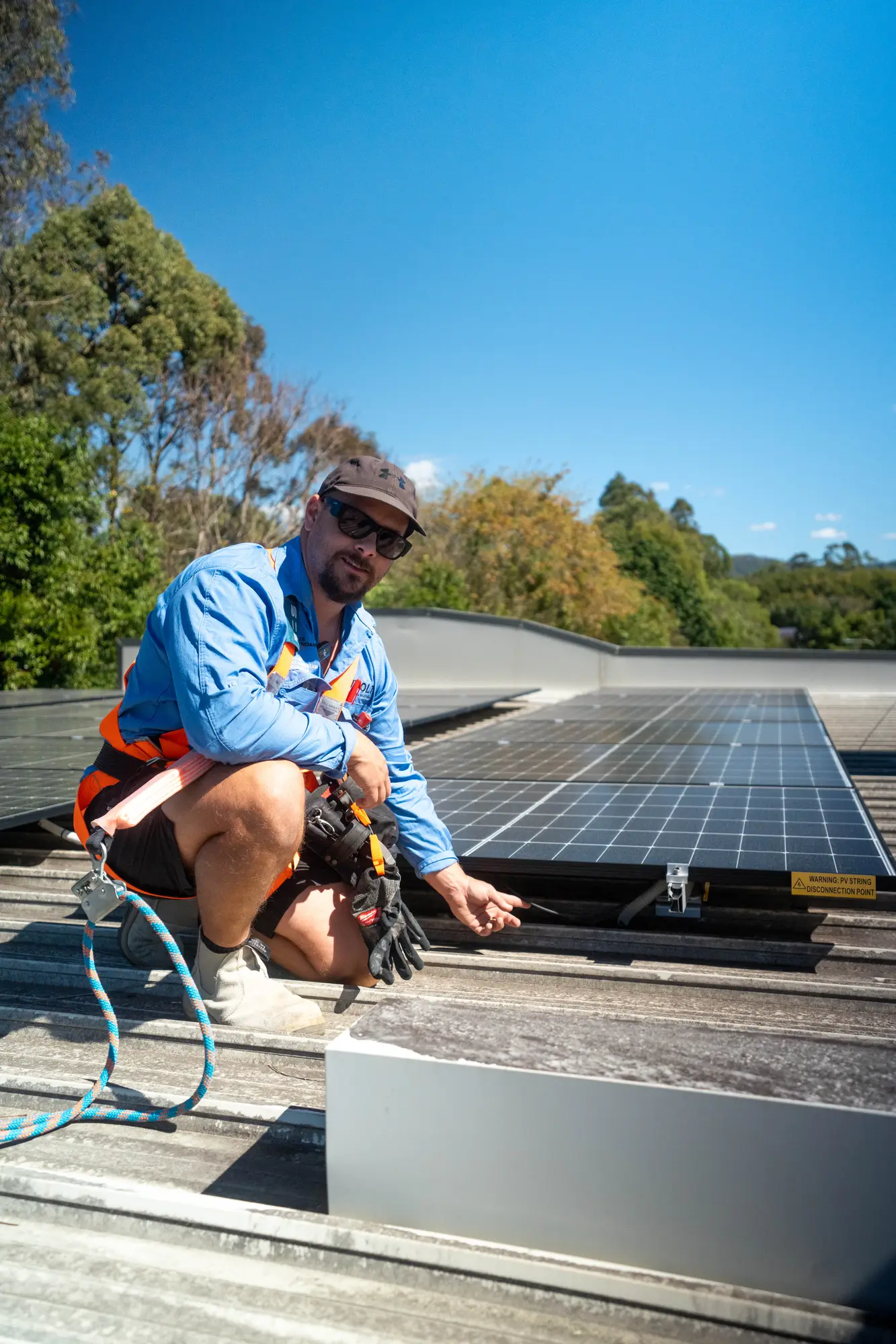 Dan from Nuvolt in a safety harness beside a solar array on a commercial metal roof