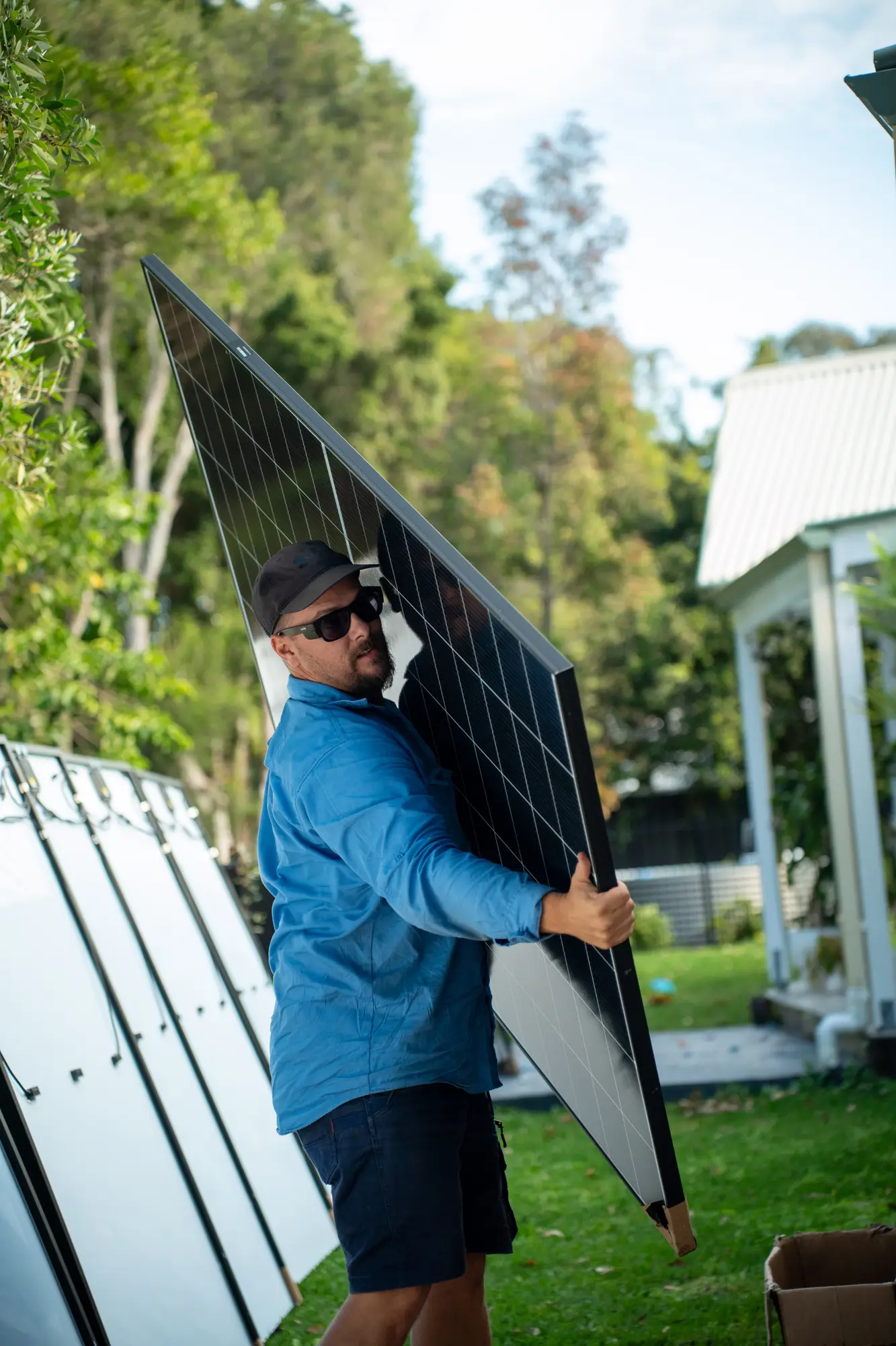 Daniel Carmont, Nuvolt's founder and licensed electrical contractor, carrying a solar panel across a backyard to the job