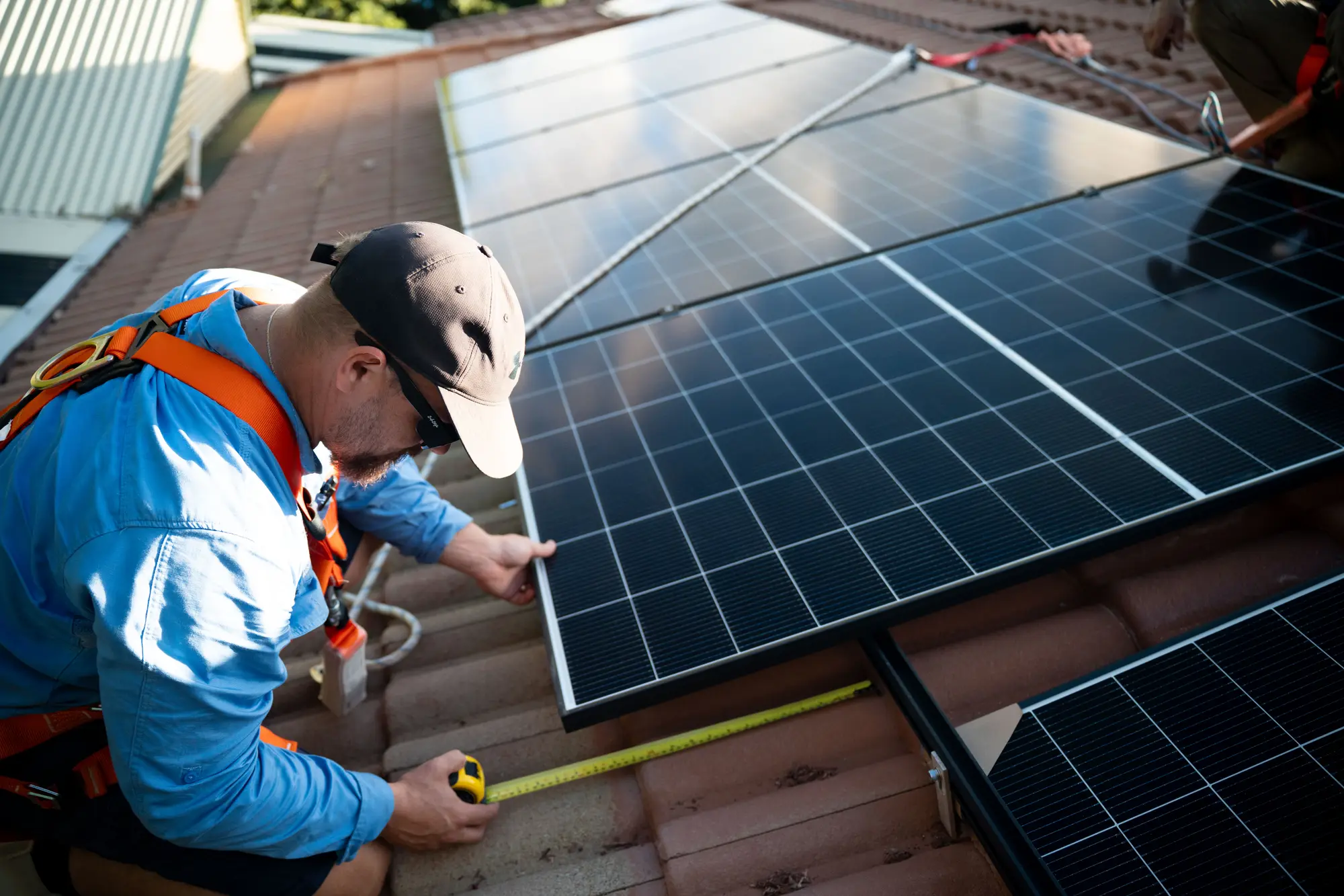 Dan from Nuvolt measuring the gap between solar panels on a roof