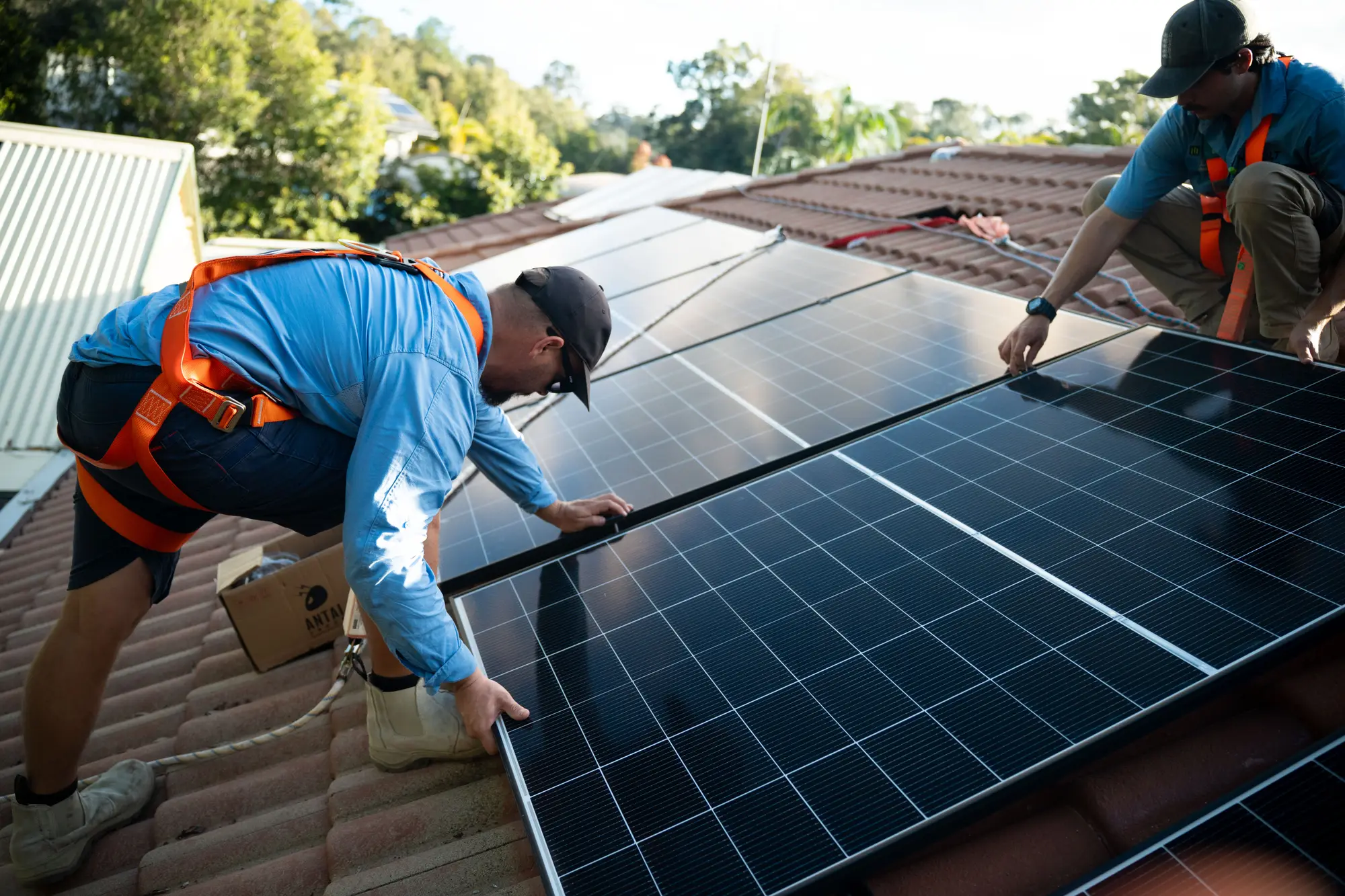 Dan from Nuvolt lining up a solar panel on a tiled roof, with a team member behind