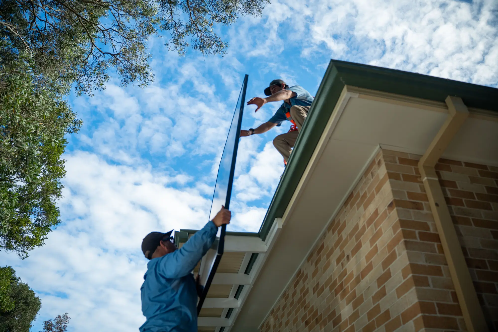 Dan from Nuvolt and a team member laying solar panels on a tiled roof on the Sunshine Coast